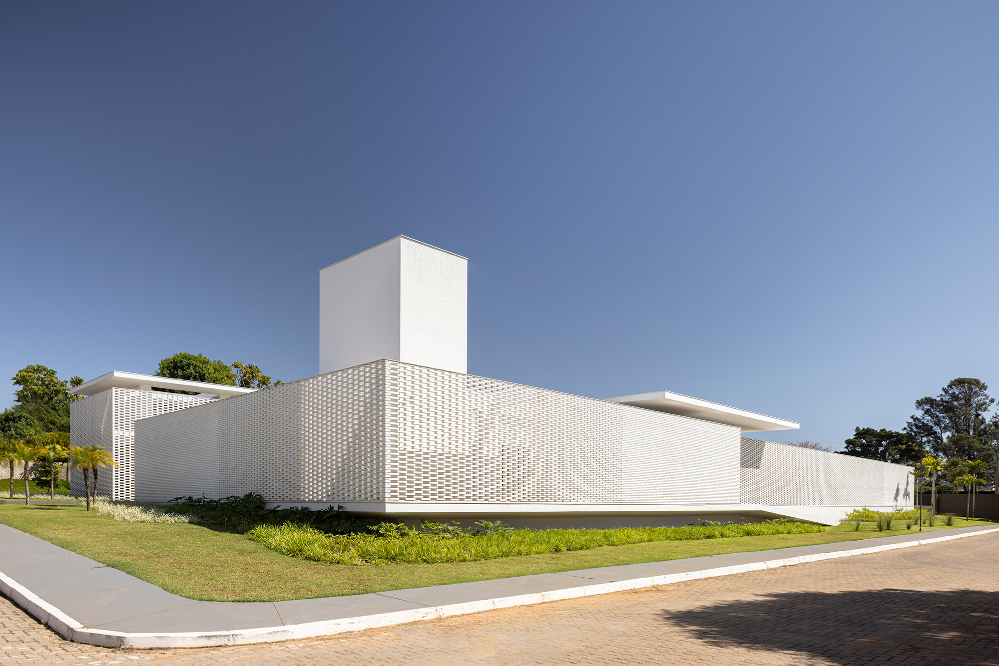 Tijolos brancos e vazados compõem fachada de casa de 600 m² em Brasília. Projeto de Bloco Arquitetos. Na foto, fachada da casa com muro de tijolos vazados.