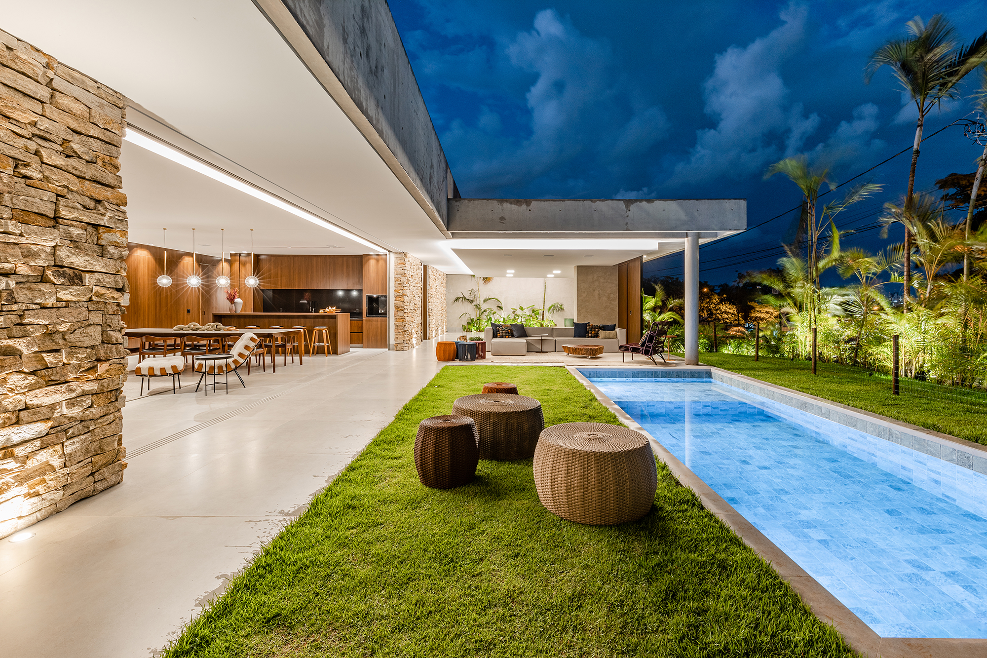 Tons escuros e grandes aberturas criam sofisticação em casa de 430 m². Projeto de Aline Borges. Na foto, jardim com piscina e fachada.