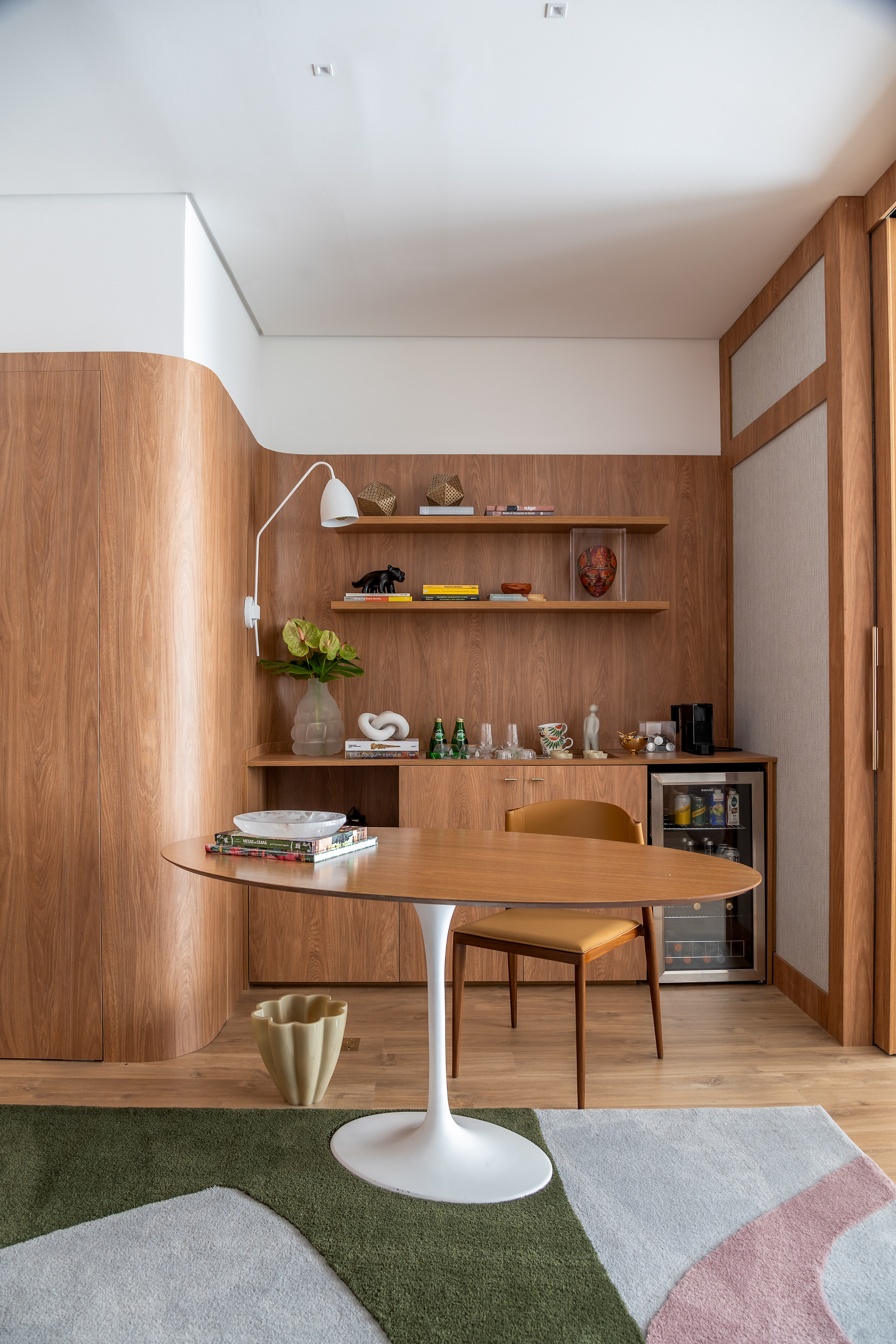 Ana Weege assina consultório psicológico com cara - e aconchego! - de casa. Na foto, sala de espera com bar, parede curva e prateleiras.