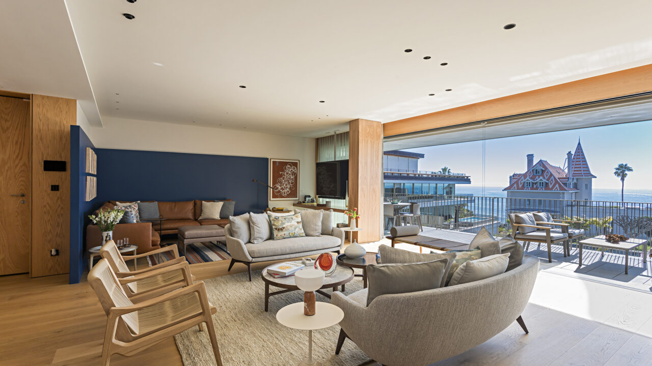 Apê contemporâneo fica em antiga propriedade real portuguesa. Projeto de Andrea Chicharo. Na foto, sala de estar e jantar com mesa e sofás. Varanda com vista para o Estoril.