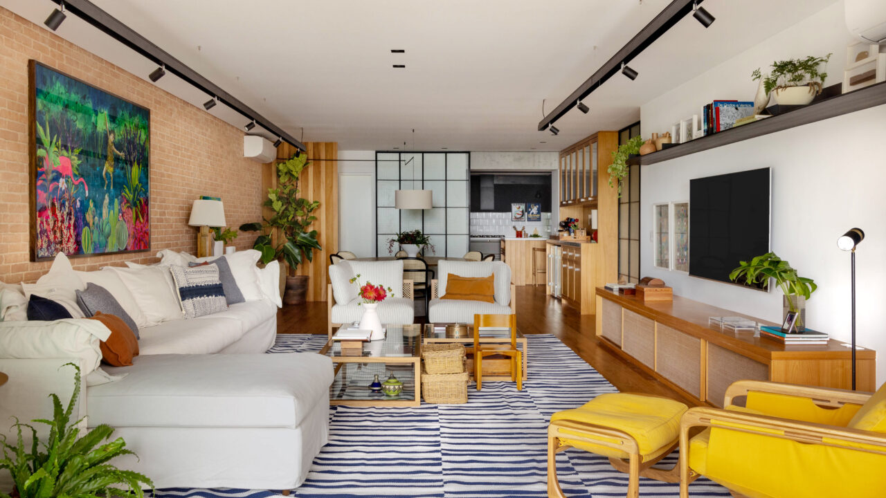 Estilos contemporâneo, industrial e retrô criam apê despojado de 180 m². Projeto Escala Arquitetura. Na foto, sala de estar, jantar e cozinha com parede de tijolos, tv e tapete.