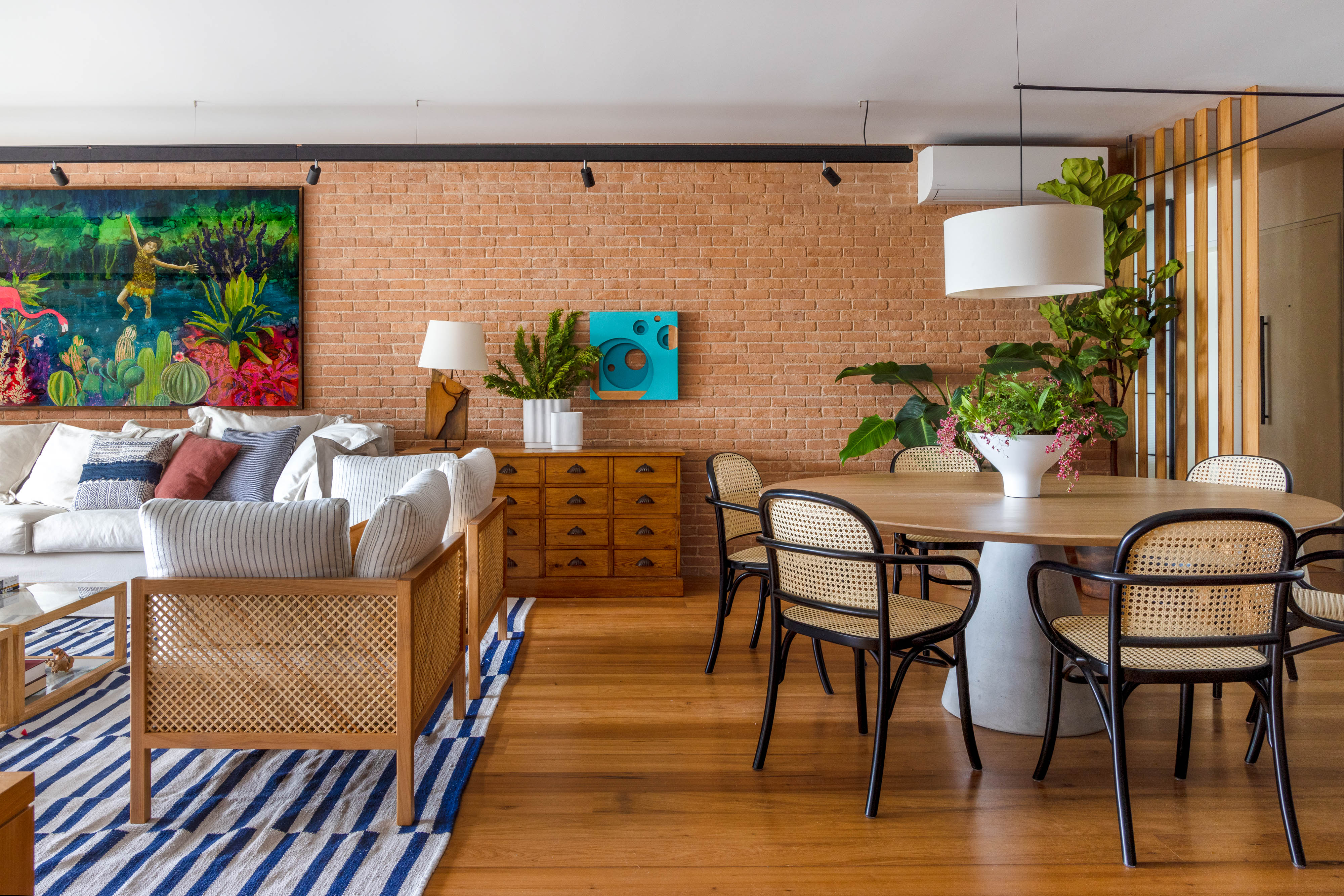 Estilos contemporâneo, industrial e retrô criam apê despojado de 180 m². Projeto Escala Arquitetura. Na foto, sala de estar e jantar com parede de tijolinho, quadros e tapete.
