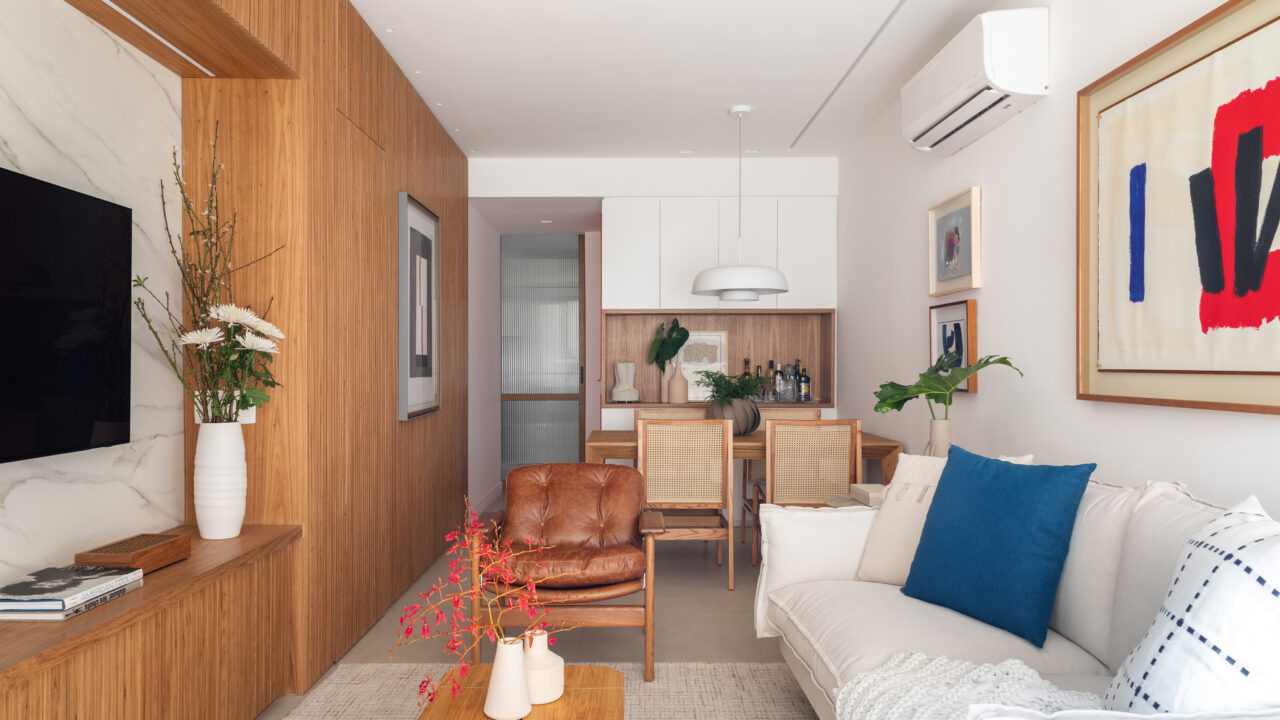 Painel ripado unifica e setoriza este apê assinado por Carmen Zaccaro. Na foto, sala de jantar com mesa de madeira e bar.