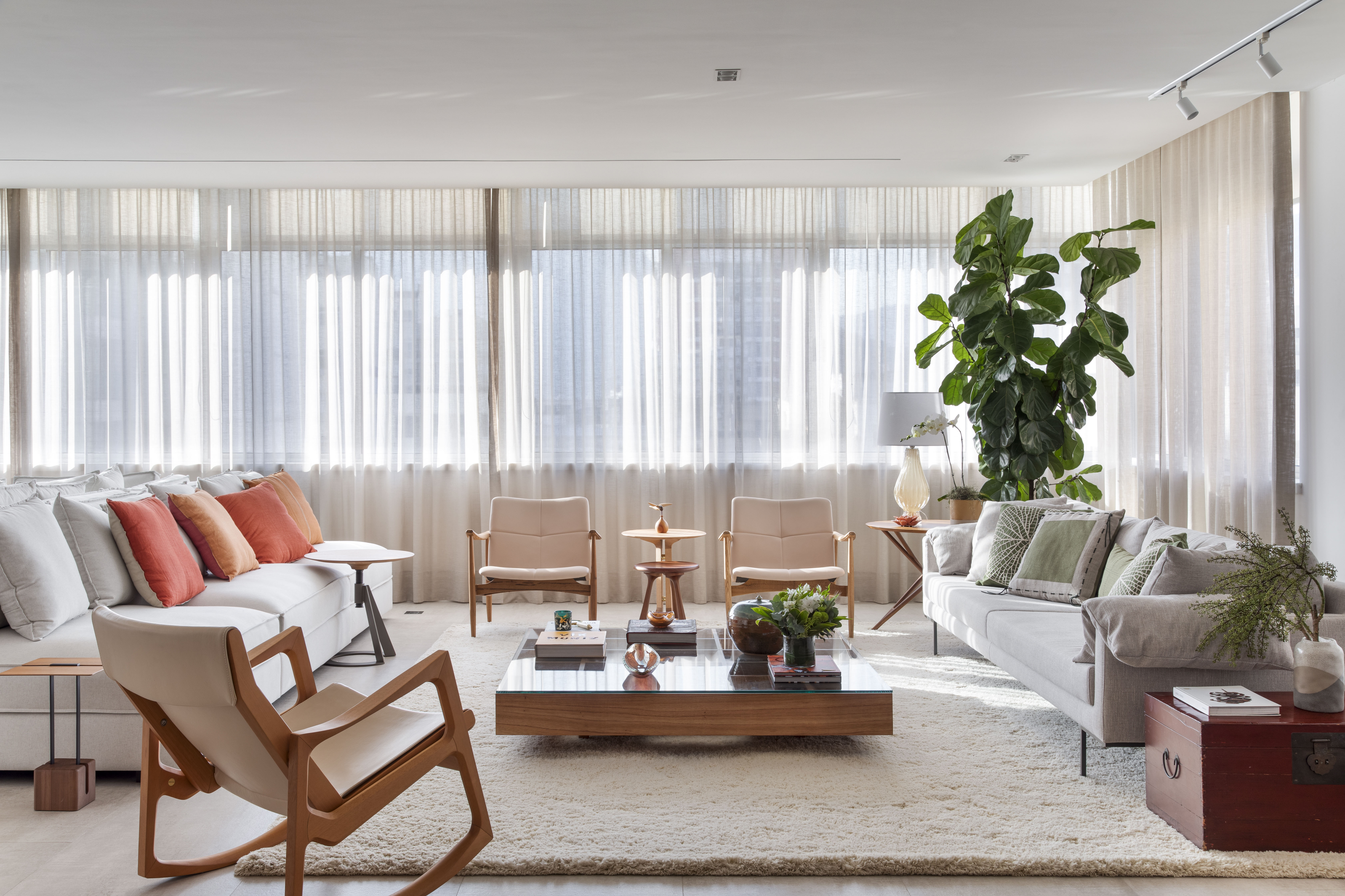Carmen Zaccaro personaliza apê com base neutra e toques pontuais de cor. Na foto, sala de estar com tapete, sofá e cortinas.