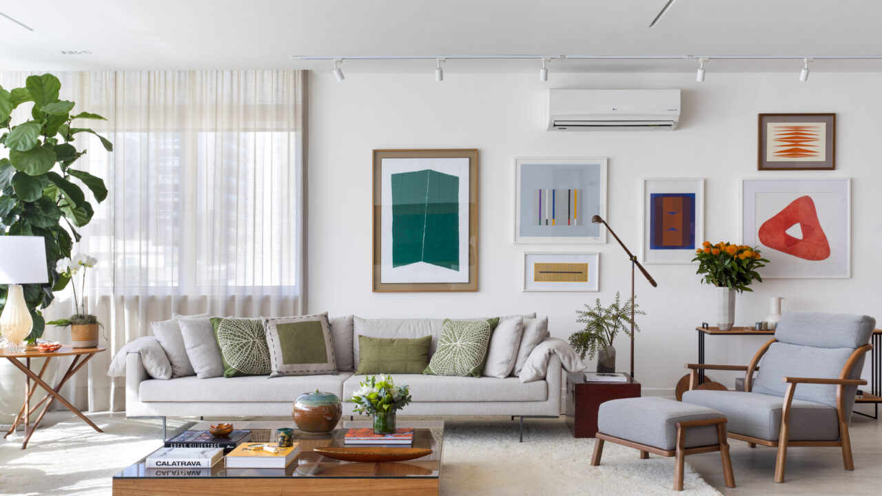 Carmen Zaccaro personaliza apê com base neutra e toques pontuais de cor. Na foto, sala de estar com sofá, tapete, quadros e mesa de centro.