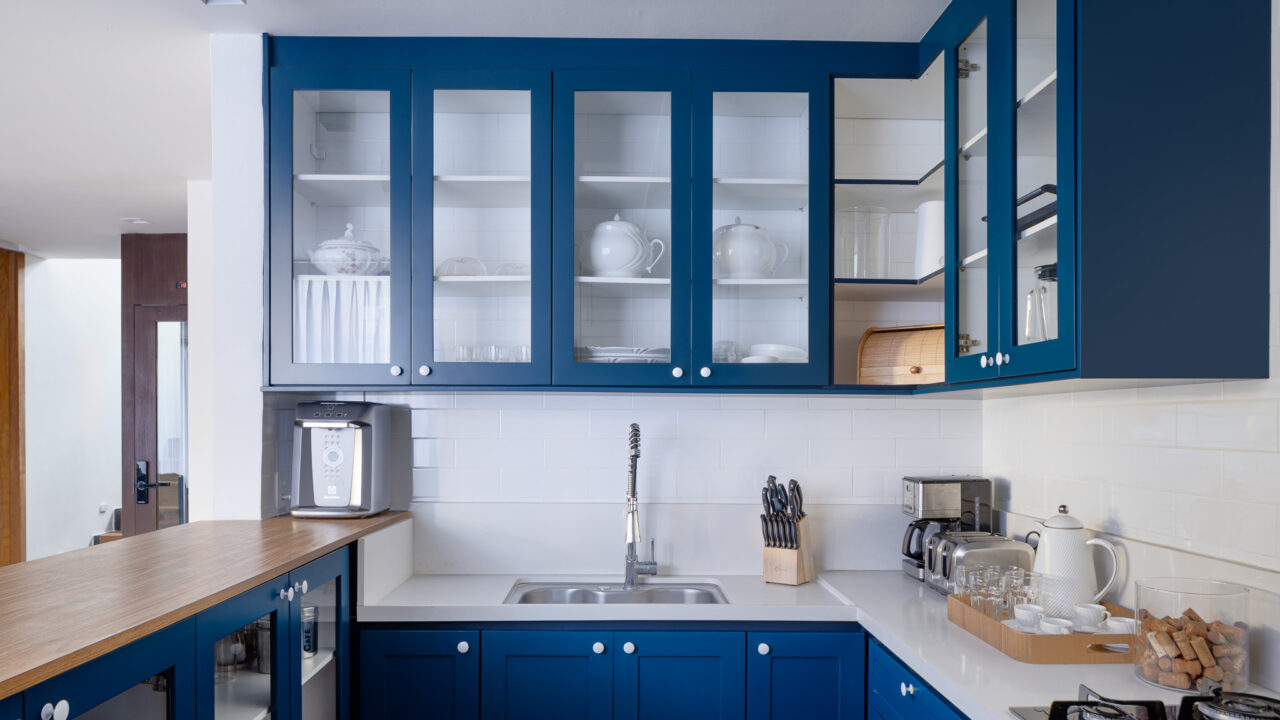Casa na serra ganha anexo com parede de pedra em projeto de Rafael Mirza. Na foto, cozinha com marcenaria azul e subway tiles.