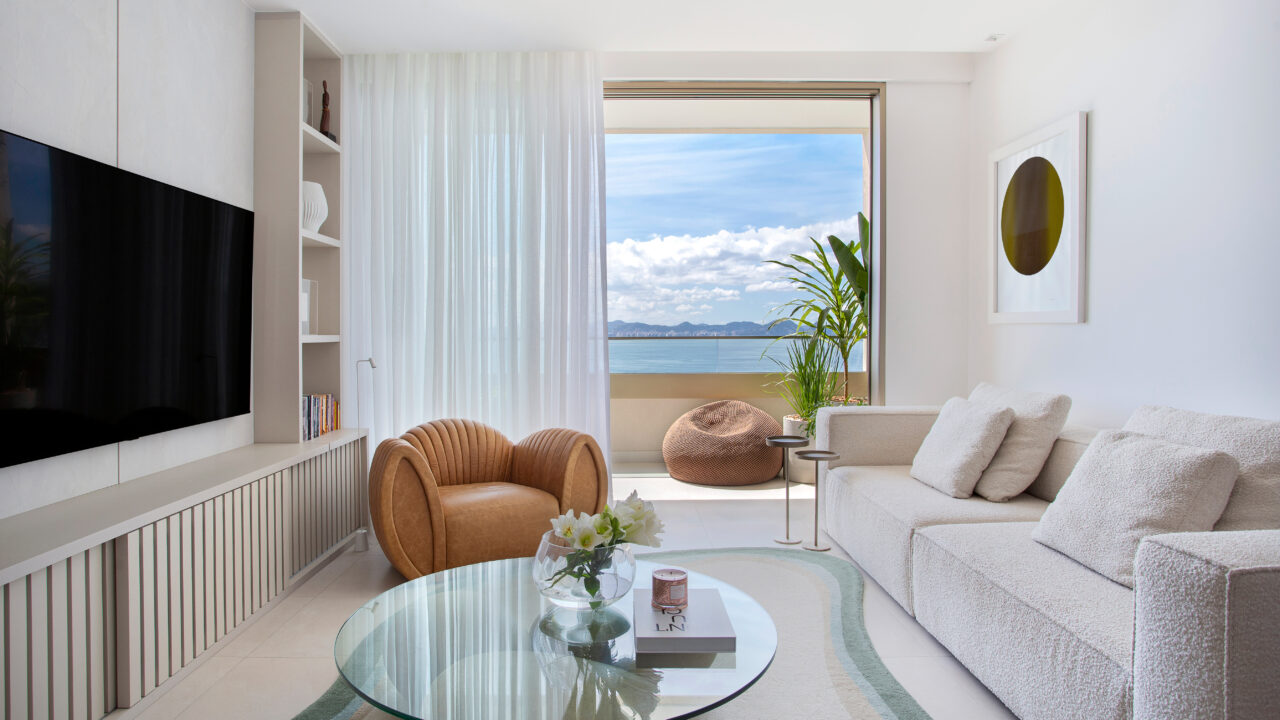 Conheça o lar da atriz Clara Moneke, assinado por Tom Castro. Na foto, sala de estar com vista para o mar, sofá e tapete.