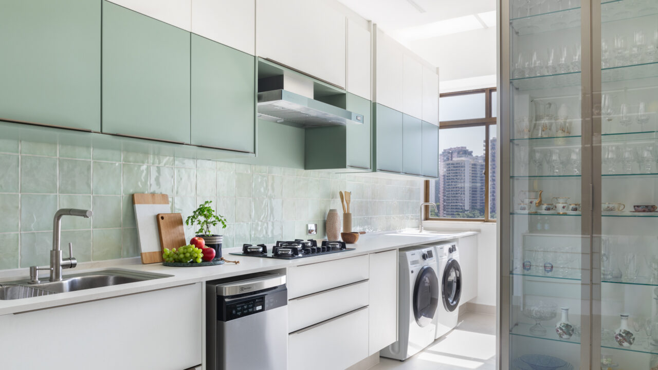 Apartamento à beira-mar ganha cara de casa com cozinha verde. Projeto de Vivian Reimers. Na foto, cozinha com parede e marcenaria verde e lavanderia integrada.