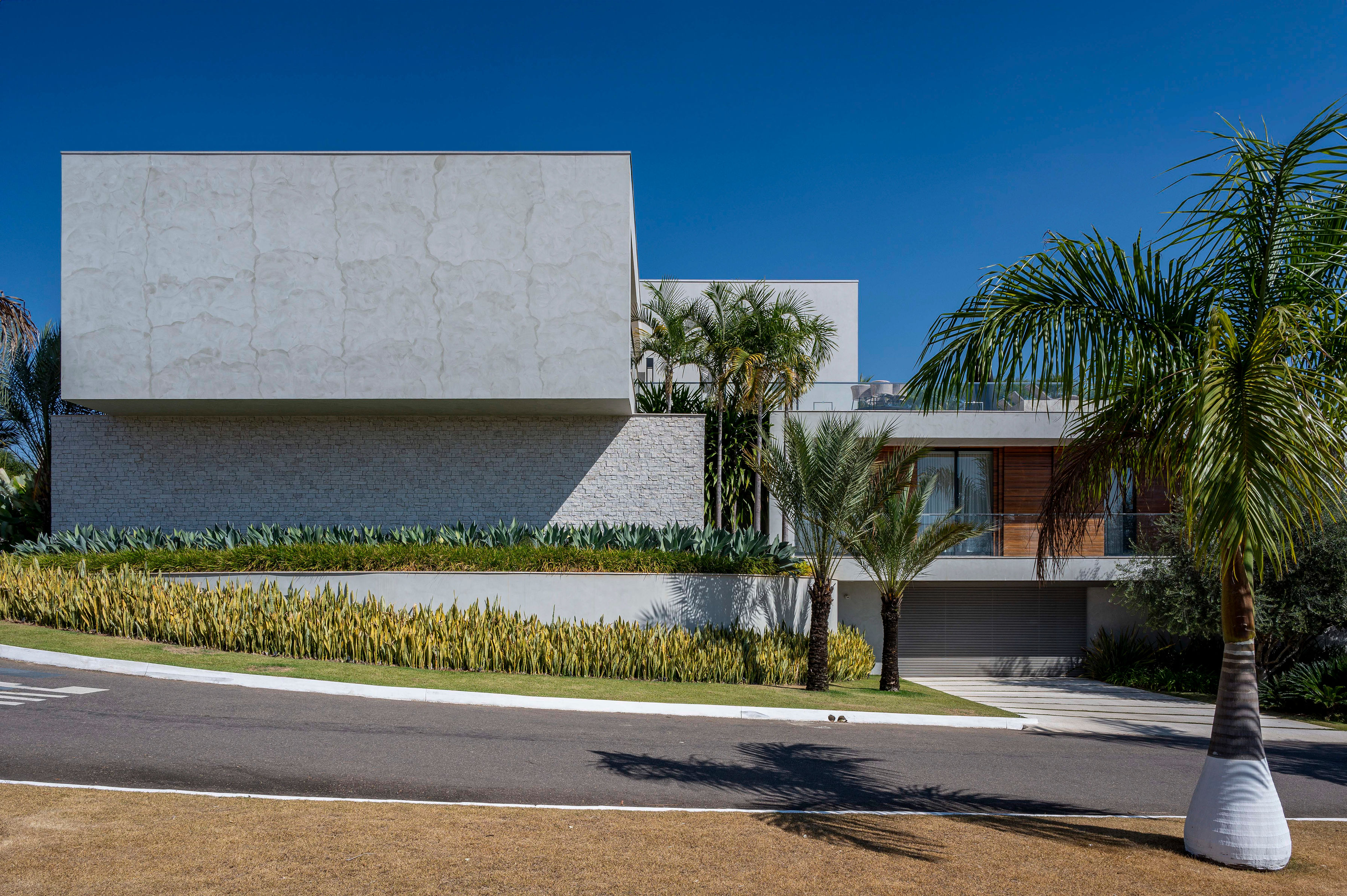 Três grandes oliveiras norteiam o paisagismo desta casa em MG. Projeto de paisagismo de Flávia D'urso. Na foto, fachada com jardim.