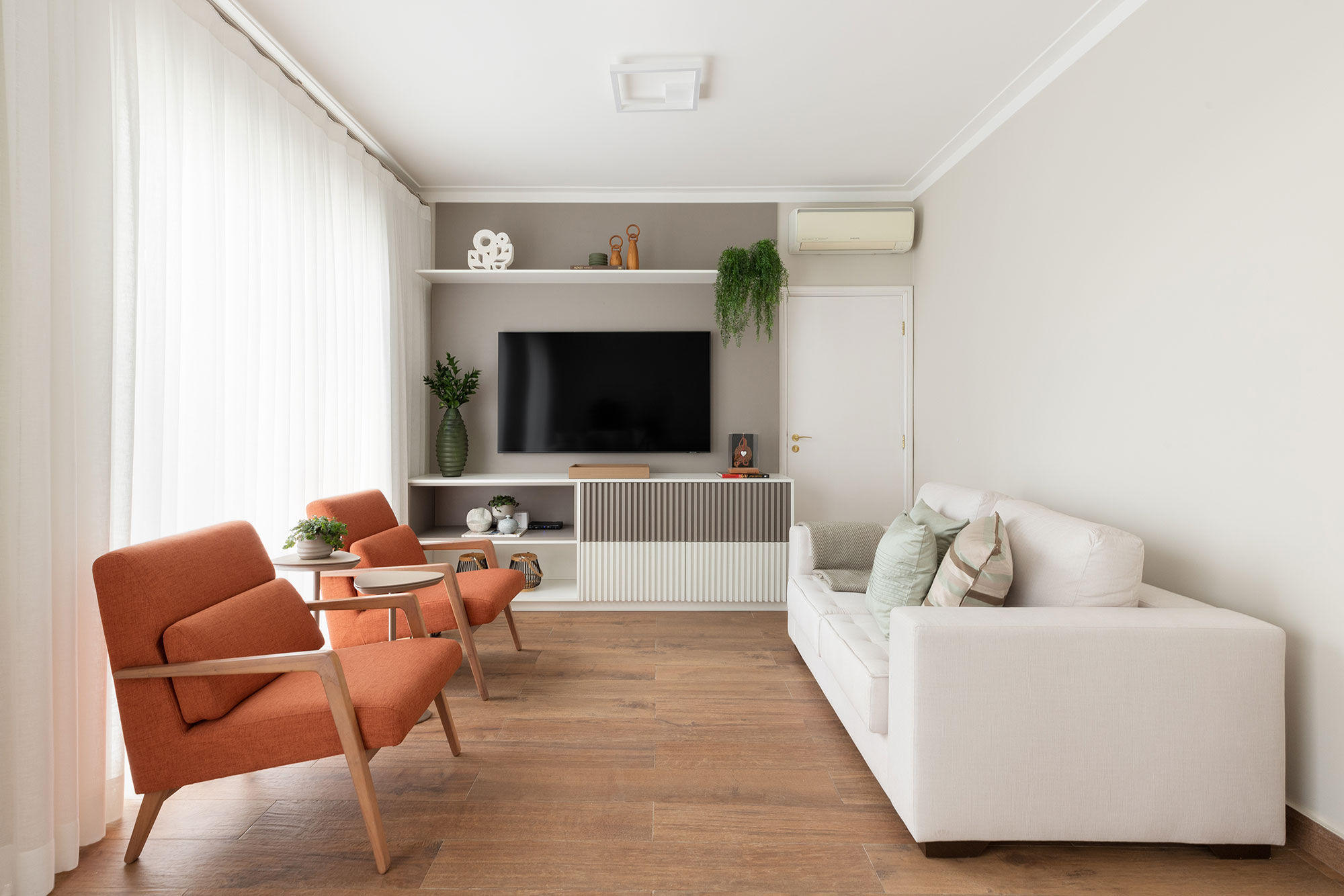 Retrofit moderniza casa no bairro histórico do Pacaembu, em São Paulo. Projeto de Daniela Funari. Na foto, sala de TV com sofá branco e poltrona.