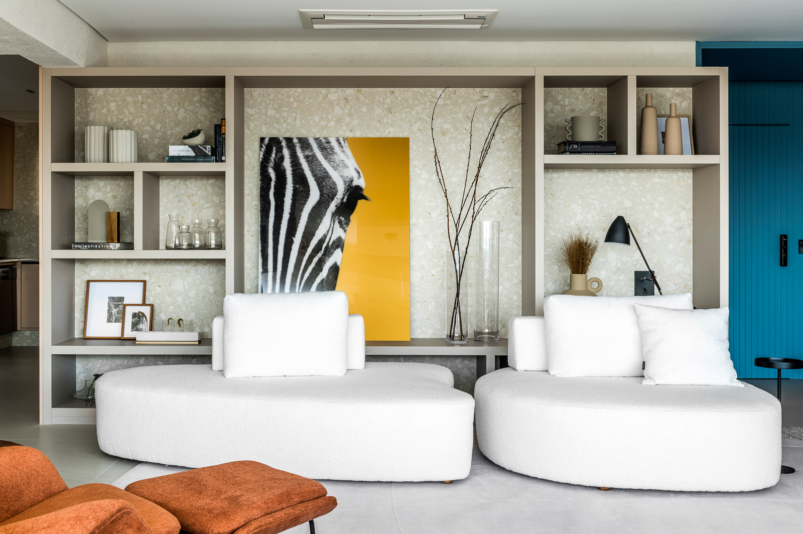 Amarelo mostarda e azul dão personalidade a apartamento de 227 m². Projeto de Tetriz Arquitetura. Na foto, sala com sofá branco e parede azul.