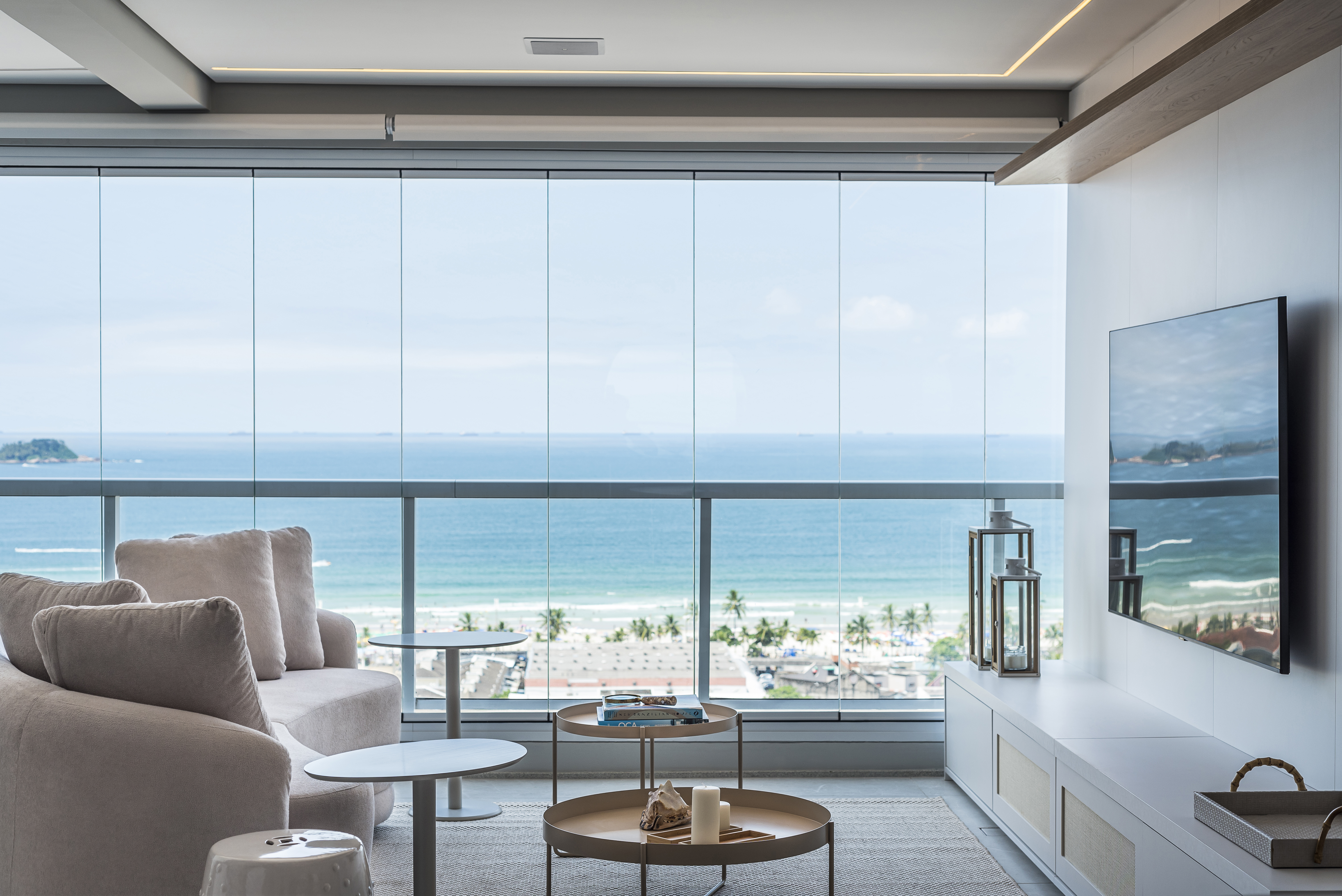 Com vista para o mar, duplex ganha décor neutro e minimalista. Projeto de Mariana Meneghisso e Alexandre Pasquotto. Na foto, sala com vista para o mar e escada.