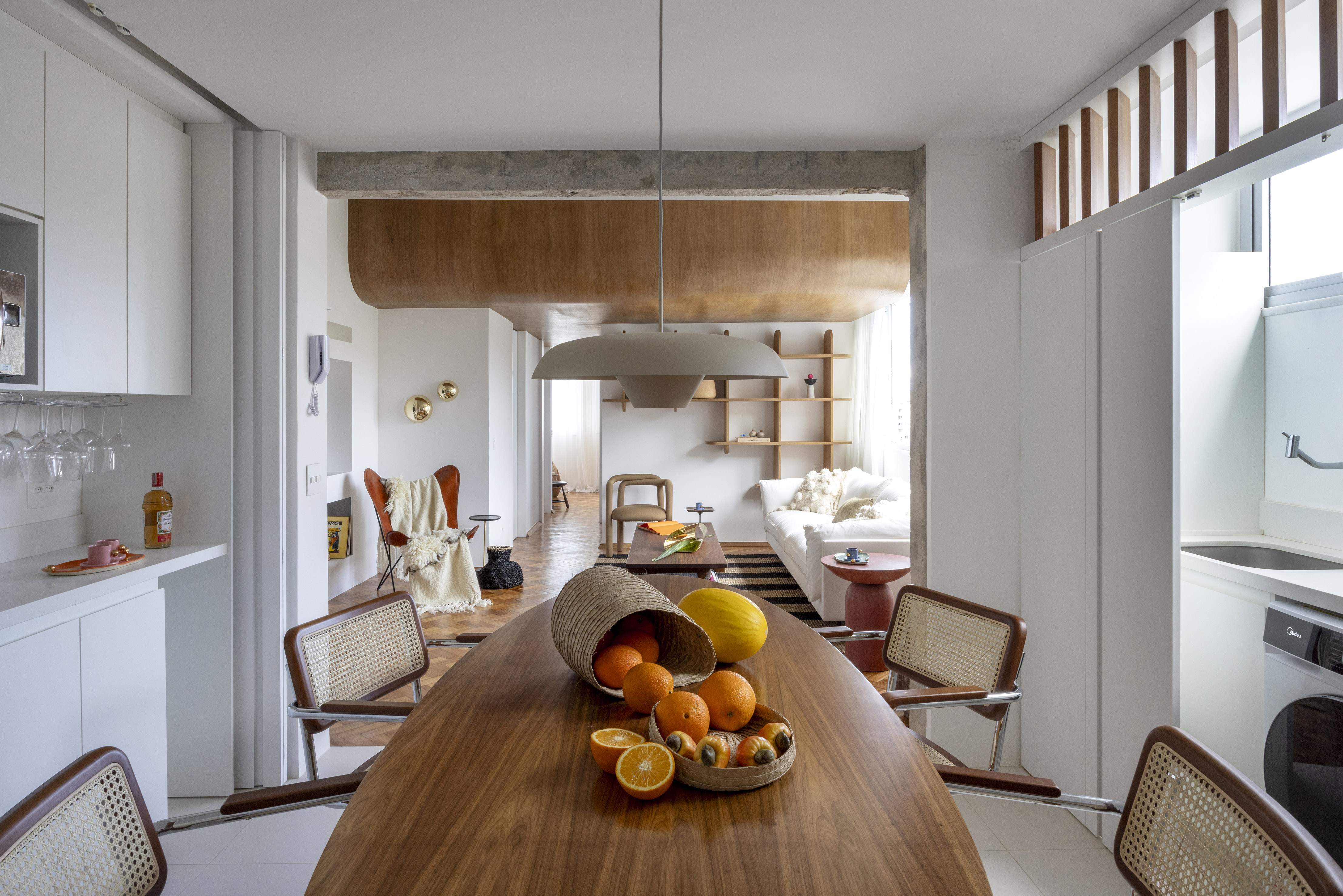 Teto curvo de madeira e parede de concreto criam personalidade neste apê. Projeto de Bric Arquitetura. Na foto, sala com cozinha integrada e parede de concreto.