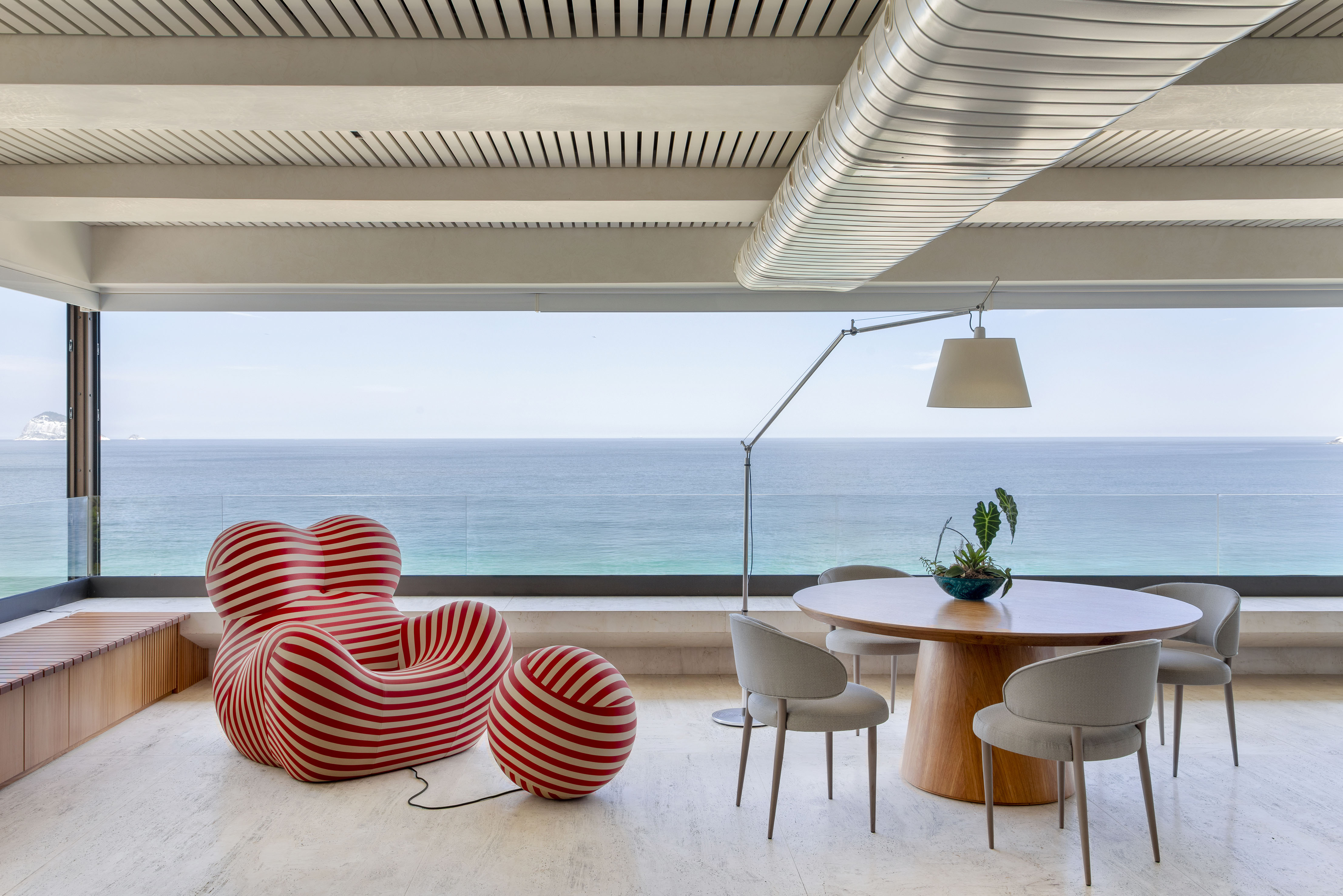 Com vista 180º do mar, apartamento de 550 m² ganha projeto jovem e solar. Projeto de 021 Arquitetura. Na foto, sala com poltrona e vista para o mar.