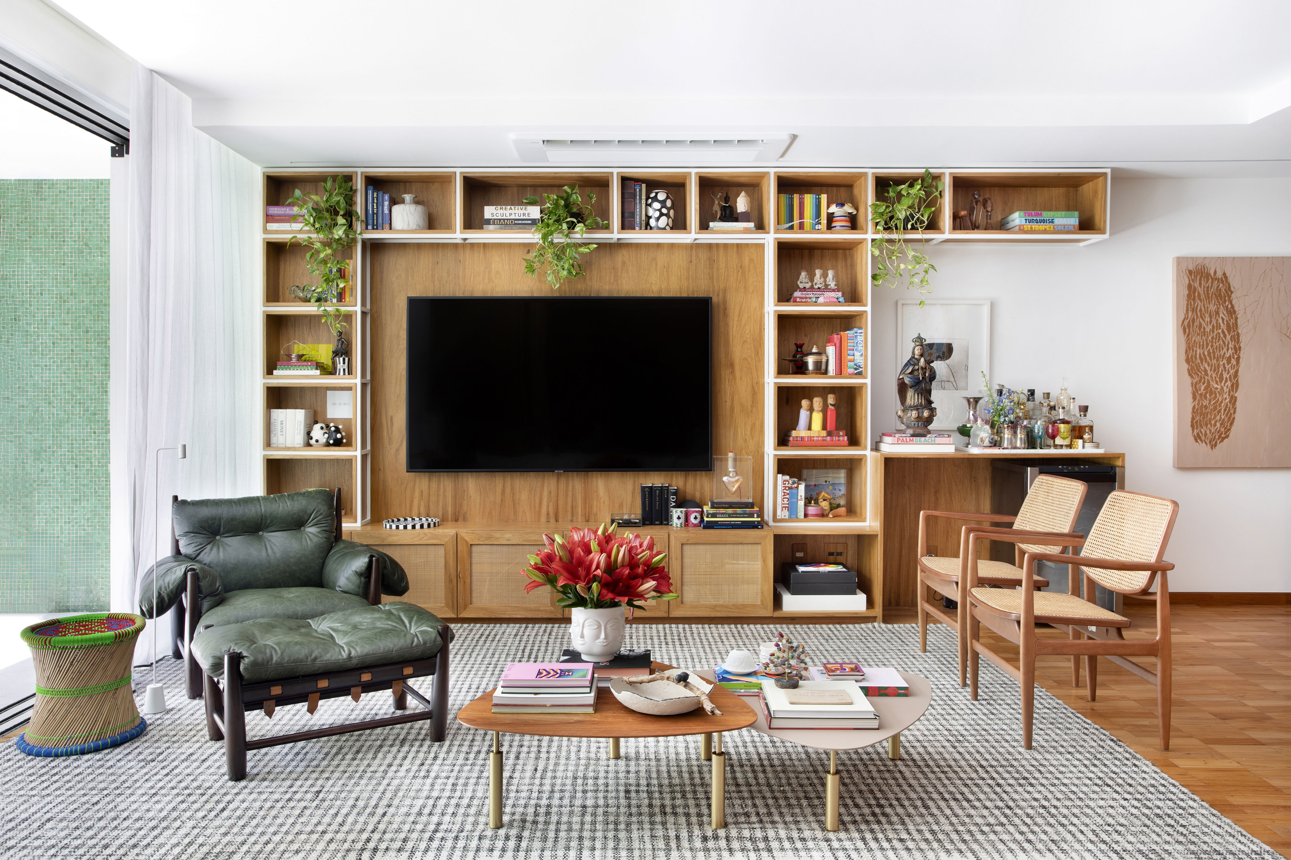 Banheiro com parede listrada e portas-camarão marcam apê de 150 m². Projeto de Bianca da Hora. Na foto, sala com estante de madeira para a TV e tapete.