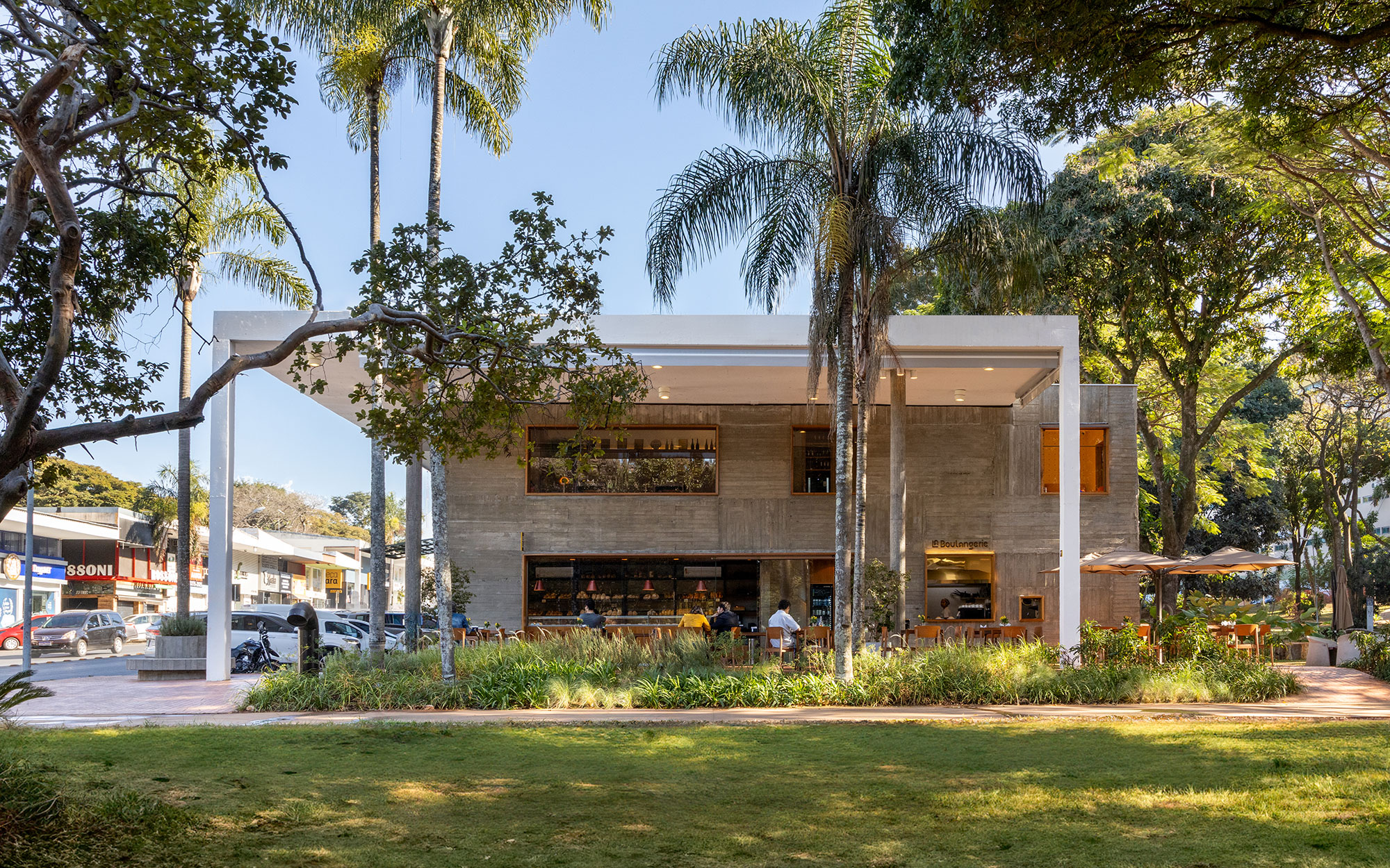 Fachada de padaria une concreto feito in loco e esquadrias de madeira. Projeto Bloco Arquitetos. Na foto, fachada e jardim.