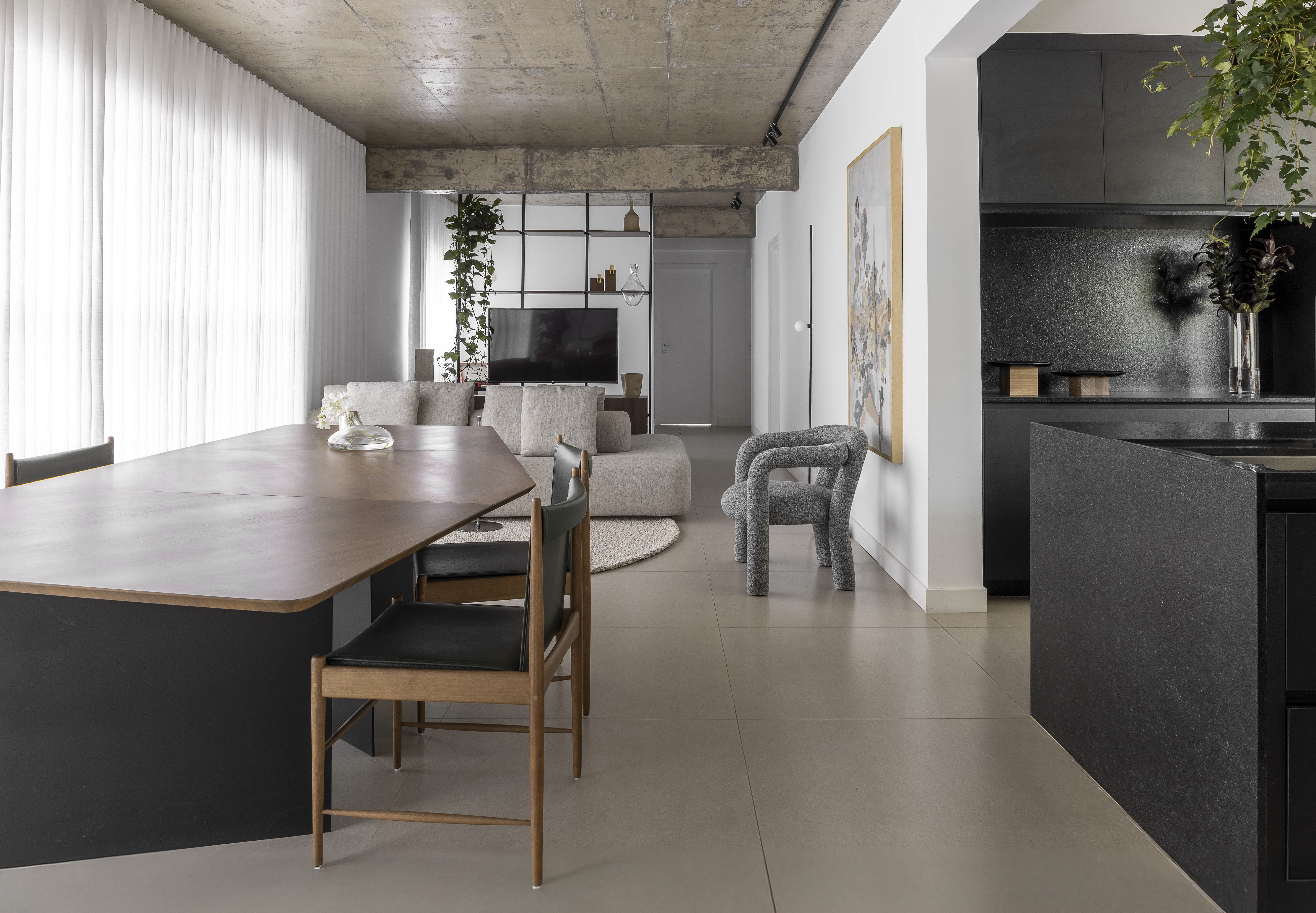 Apartamento de 150 m² mescla materiais naturais e estilo urbano. Projeto de Junior Piacesi. Na foto, sala e cozinha integrada em tons de cinza e branco.